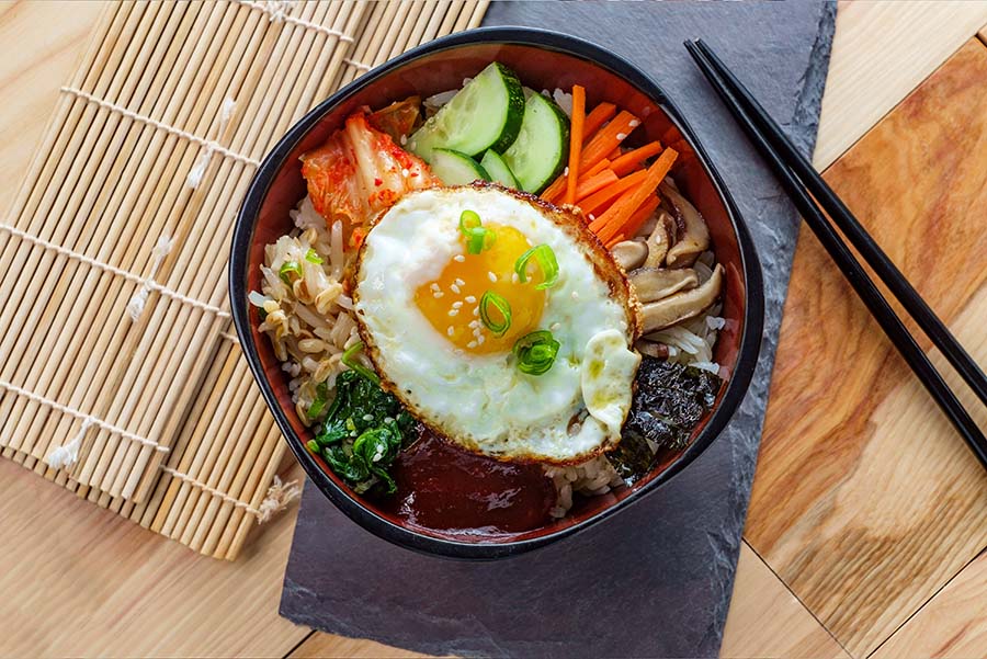 comida coreana Bibimbap, hay un huevo frito y muchas verduras