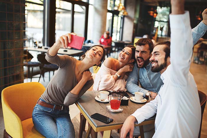 Cuatro personas estan tomando sus fotos en la cafeteria 