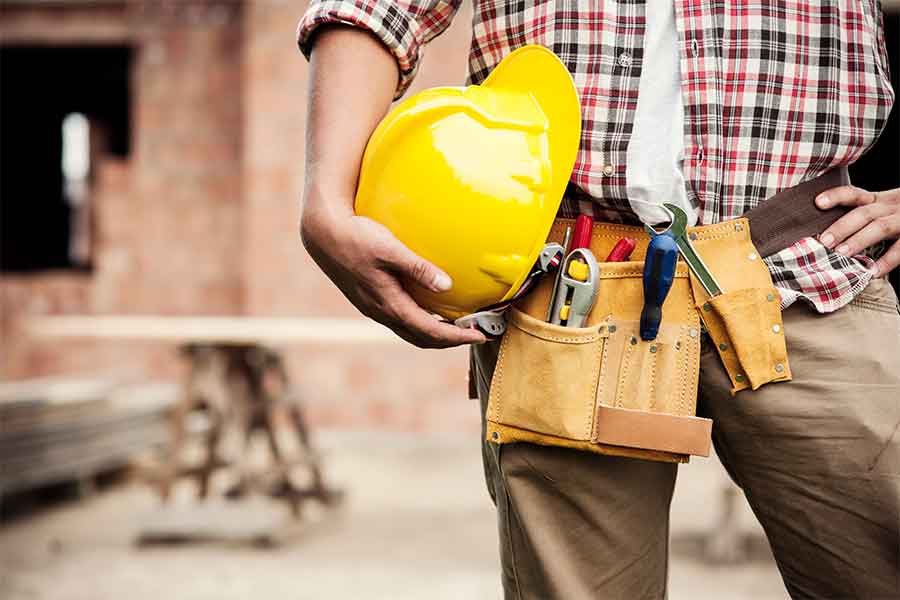 Un hombre sostiene un casco de seguridad amarillo en una mano.