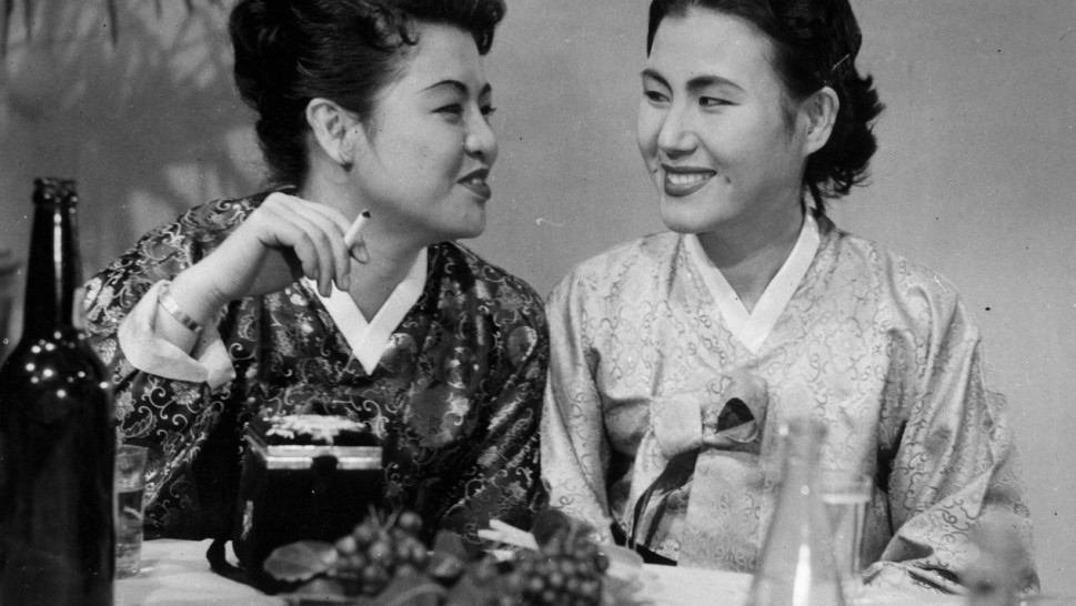 Foto en blanco y negro: dos mujeres con hanbok, una de ellas con un cigarrillo en la mano.
